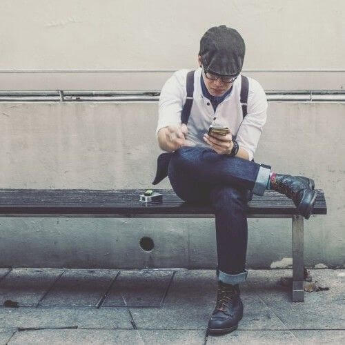 Men uses smartphone sitting on the bench