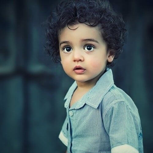 Boy with curly hair and dark eyes looking at the lens